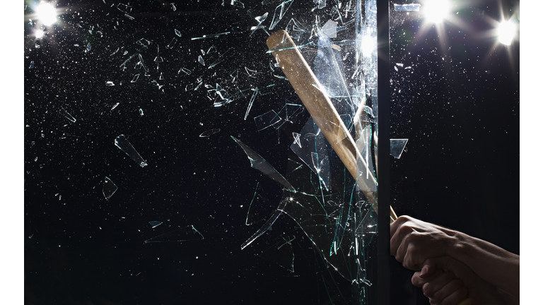 Detail of a man smashing glass with a baseball bat