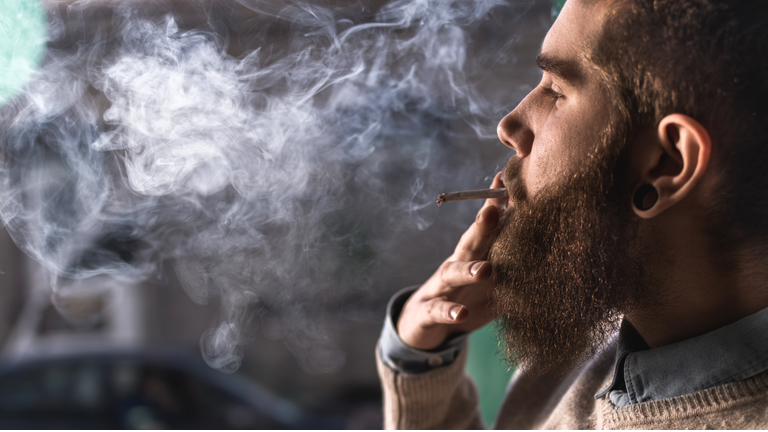 Close up of a young hipster smoking cigarette.