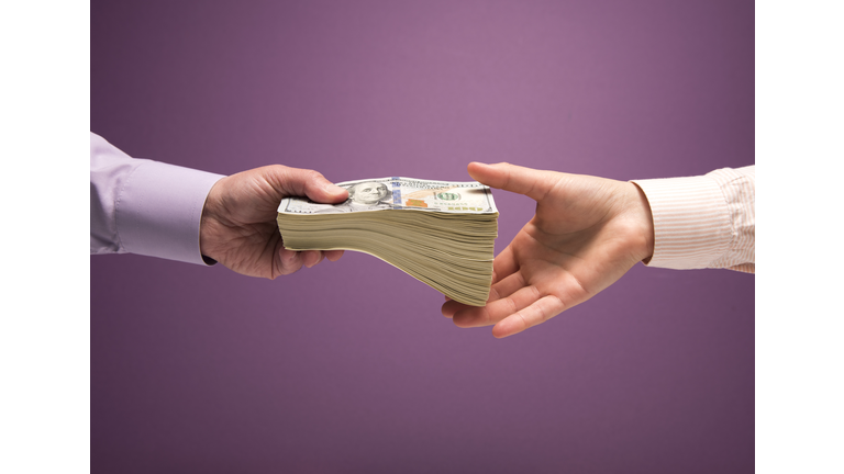 Man and woman's hands handing pile of cash
