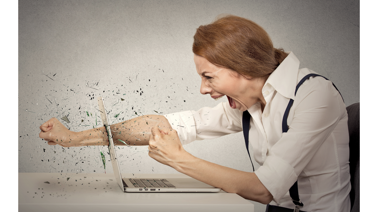 Furious businesswoman throws a punch into computer, screaming