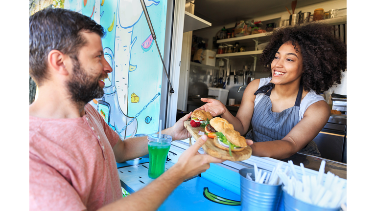 Food truck owner serving sandwiches to customer