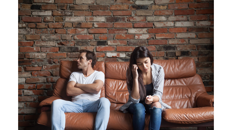 Frustrated upset couple after quarrel sitting on sofa at home