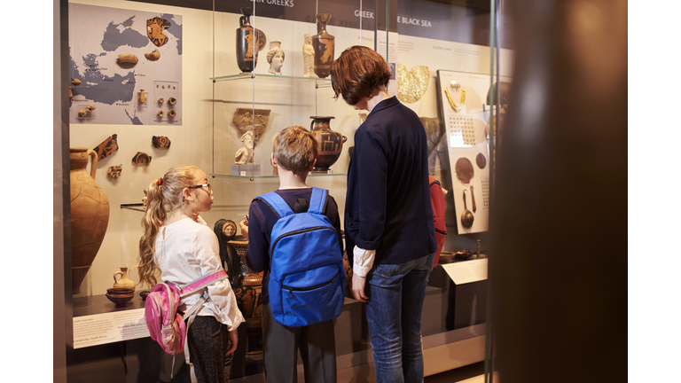 Teacher And Pupils Looking At Artifacts On Display In Museum