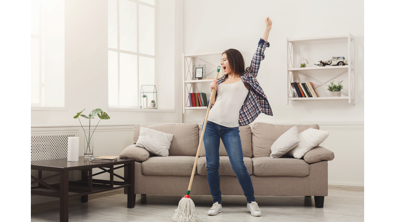 Happy woman cleaning home with mop and having fun