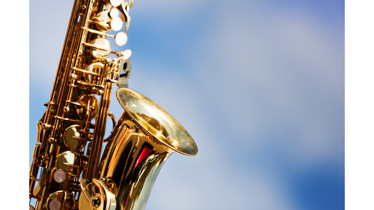 Alto sax close up against sky with scattered clouds