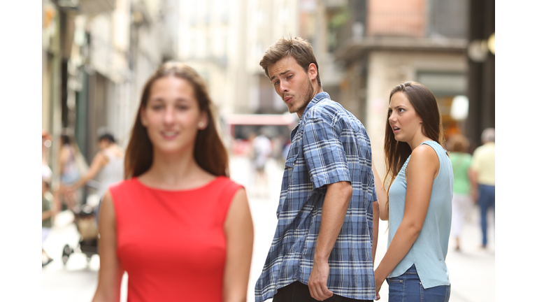 Disloyal man with his girlfriend looking at another girl