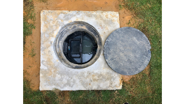 A hole of grease trap underground tank with the drain system around the house.