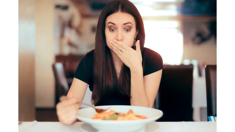 Woman Feeling Sick While Eating Bad Food in a Restaurant