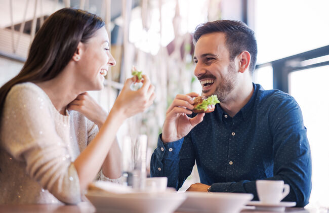 Beautiful young couple sitting in a cafe, having breakfast. Love, food, lifestyle