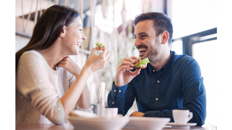 Beautiful young couple sitting in a cafe, having breakfast. Love, food, lifestyle