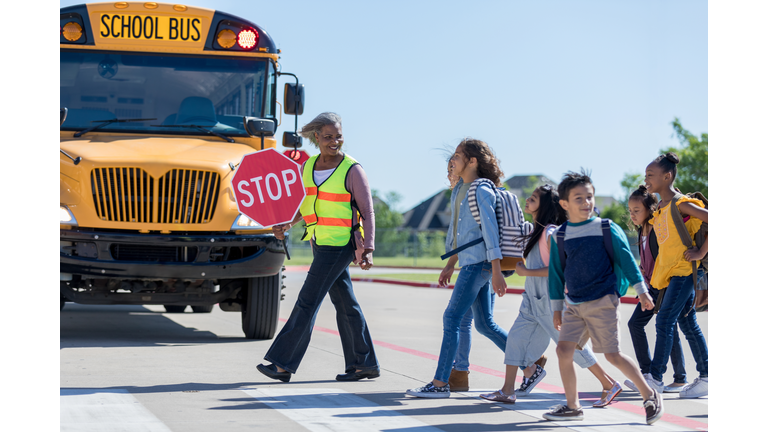 School children cross the street with crossing guard