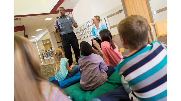 Police or school security officer speaking to young students