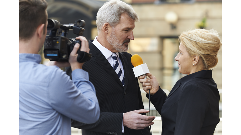 Female Journalist With Microphone Interviewing Businessman