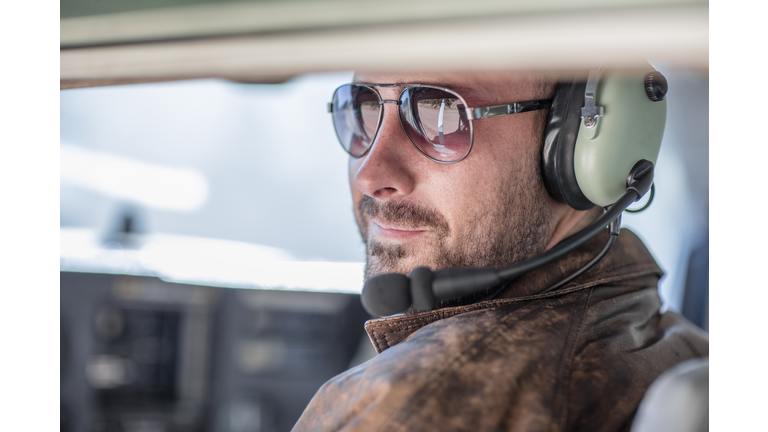 Young pilot sitting in cockpit, portrait