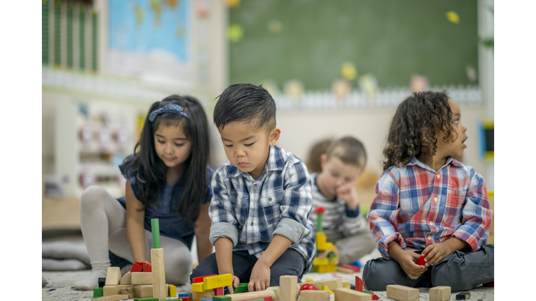 Toddlers play with wooden blocks in preschool