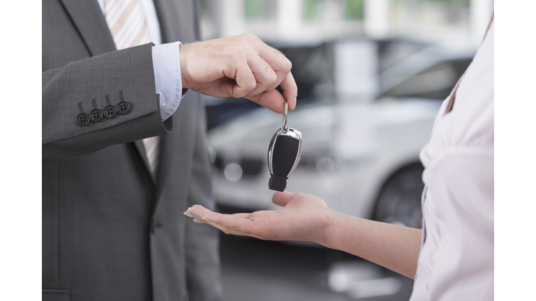 At the car dealer, Salesman handing over car key to client