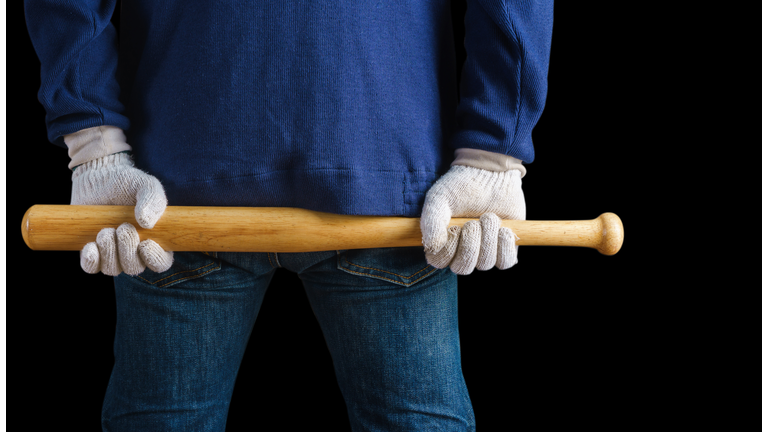 Man holding a baseball bat on black background