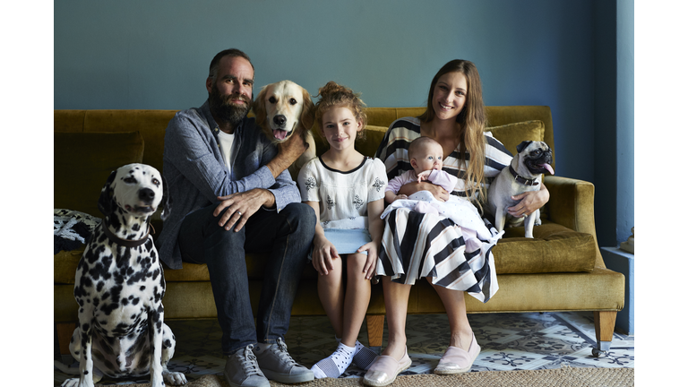 Family sitting together in sofa with their dogs