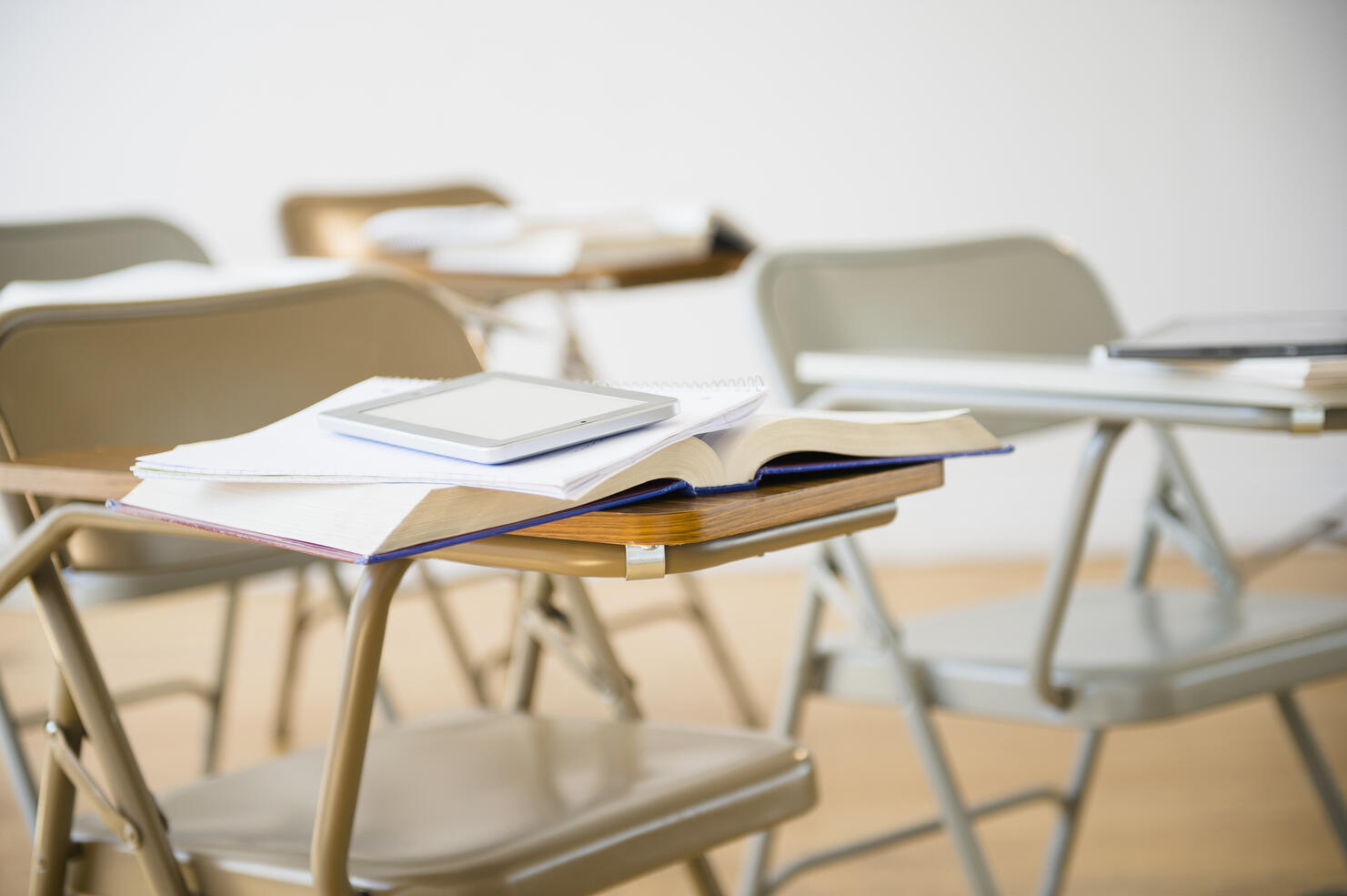 Digital tablet and book on desk in classroom