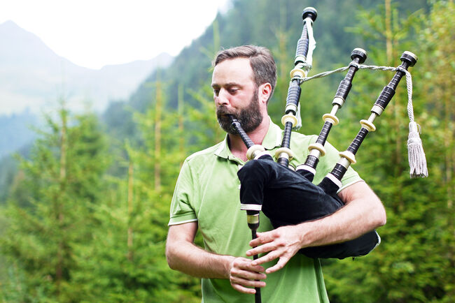 Young adult man playing bagpipe in natural surroundings