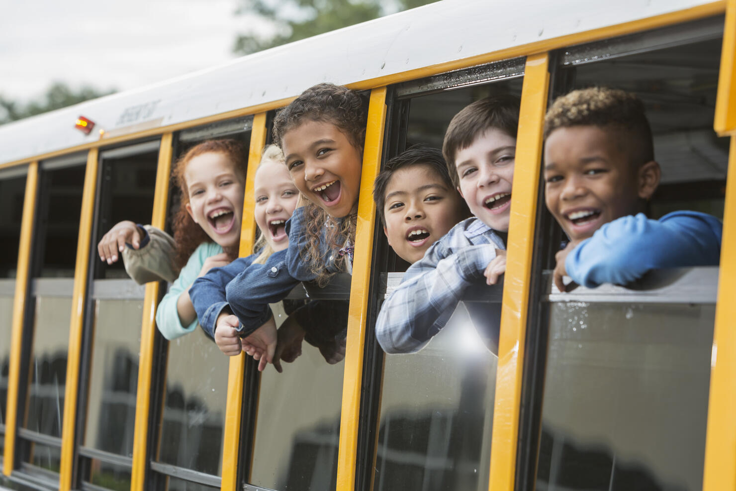 Elementary school children looking out window of bus