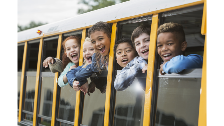 Elementary school children looking out window of bus