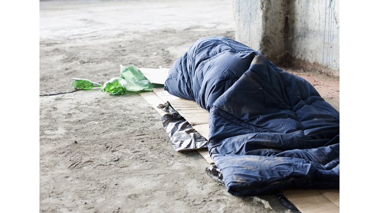 Homeless man sleeping in sleeping bag on cardboard