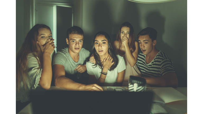 College students watching scary movie on laptop