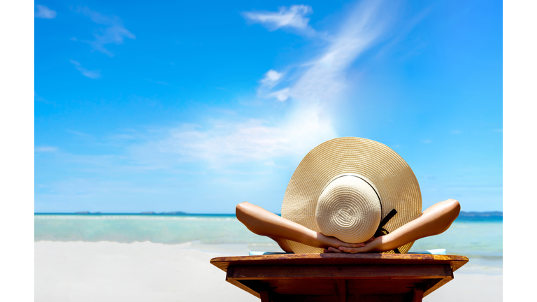 Bikini woman sexy in relax beach and resting resort in vacation on summer season with sunhat sitting chair sunbath with swimsuit alone at island lifestyle on weekend holidays