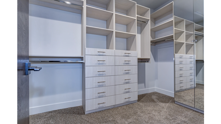 Large walk-in closet with white shelves, drawers