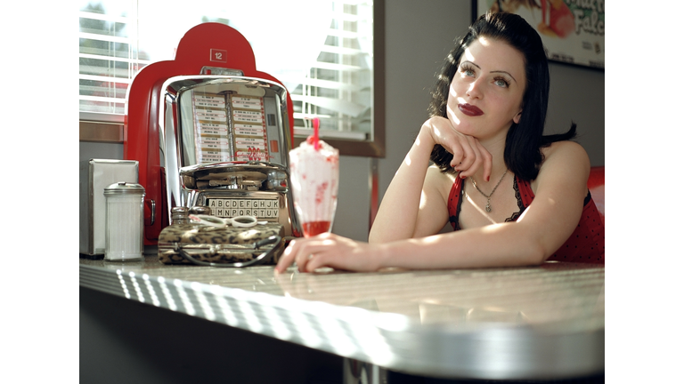 Young woman in diner, resting chin on hand, looking upwards