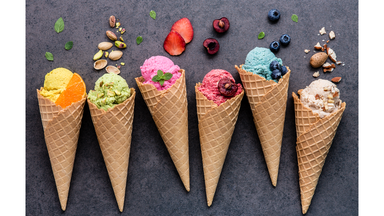 Various of ice cream flavor in cones blueberry ,strawberry ,pistachio ,almond ,orange and cherry setup on dark stone background . Summer and Sweet menu concept.