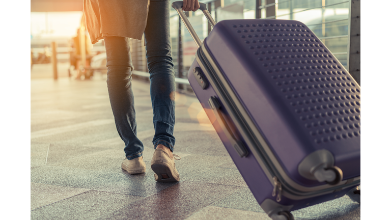 Traveler with suitcase in airport concept.Young girl  walking with carrying luggage and passenger for tour travel booking ticket flight at international vacation time in holiday rest and relaxation.