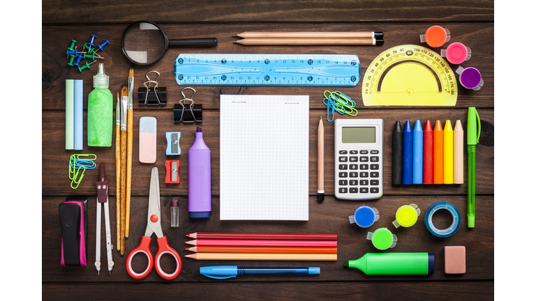 Top view of a large group of school or office supplies on wooden table