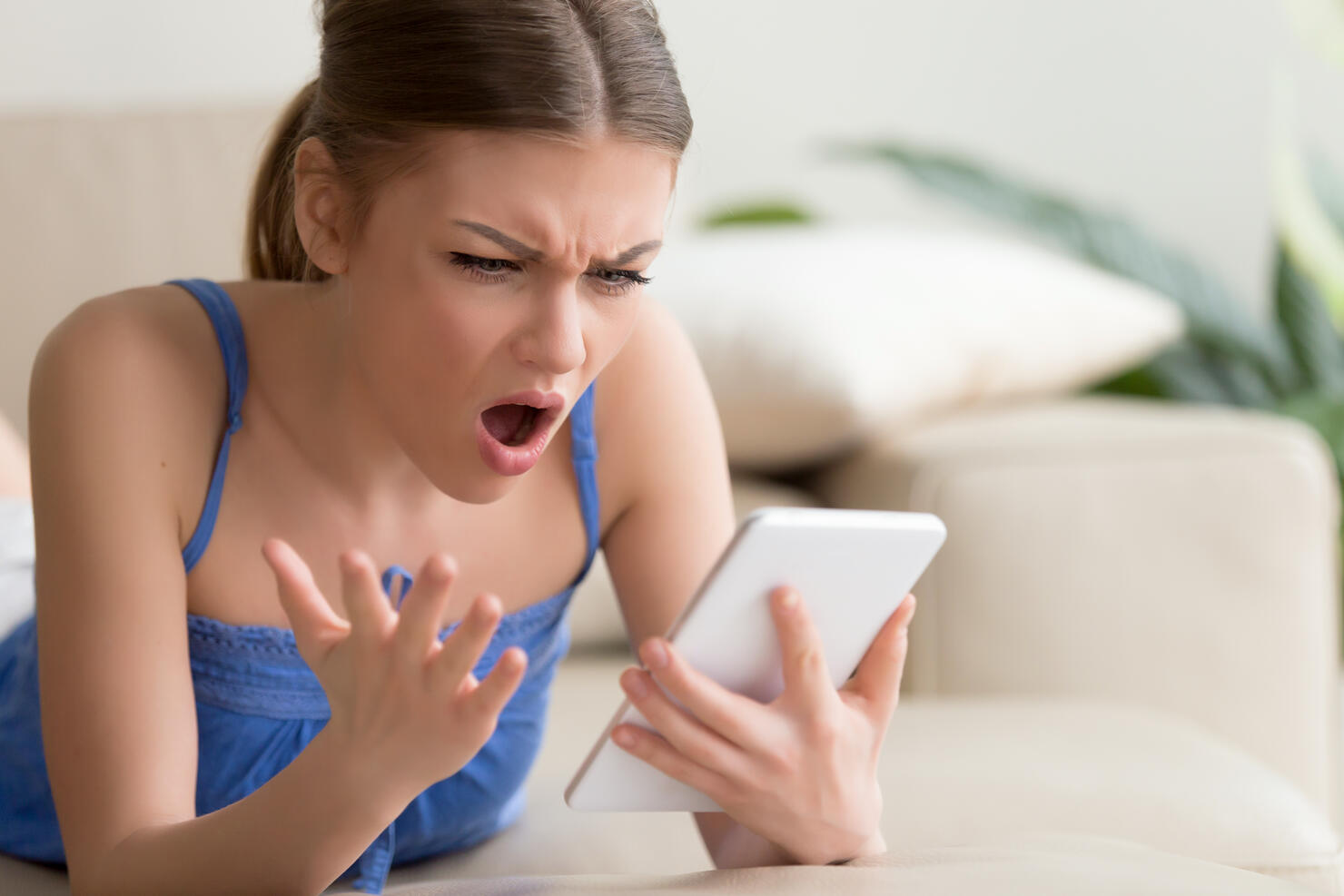 Shocked young woman using digital tablet at home