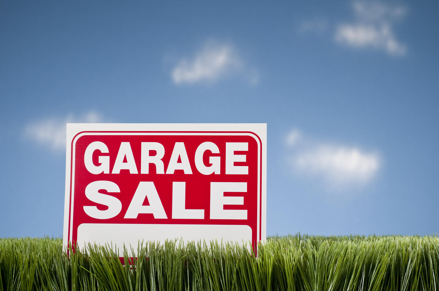 Garage Sale Sign In Grass Against Blue Sky