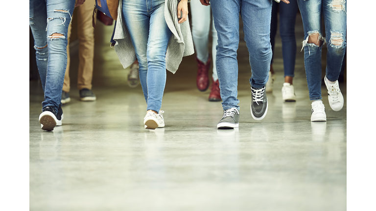 High school students walking in corridor, low section