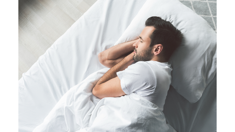 Cute young man sleeping on bed