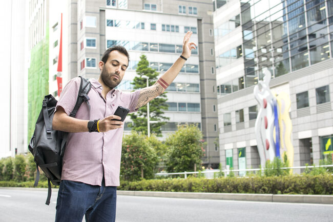 Young White Man Holding A Cellphone Hailing Uber Taxi