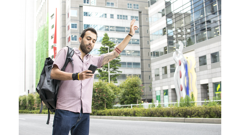 Young White Man Holding A Cellphone Hailing Uber Taxi