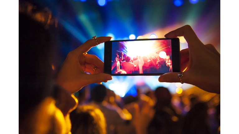 Woman taking a photo with phone at music event