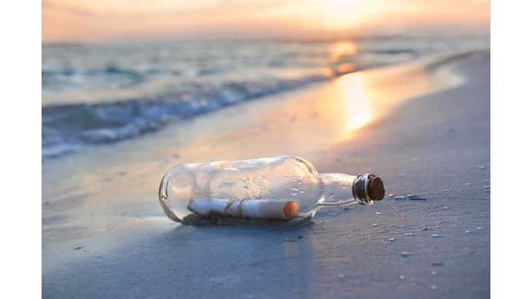 Message in a glass bottle on a beach at sunset