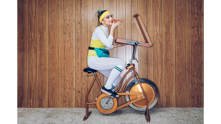 Retro Style Exercise Bike Woman Eighties Era Eating Pizza