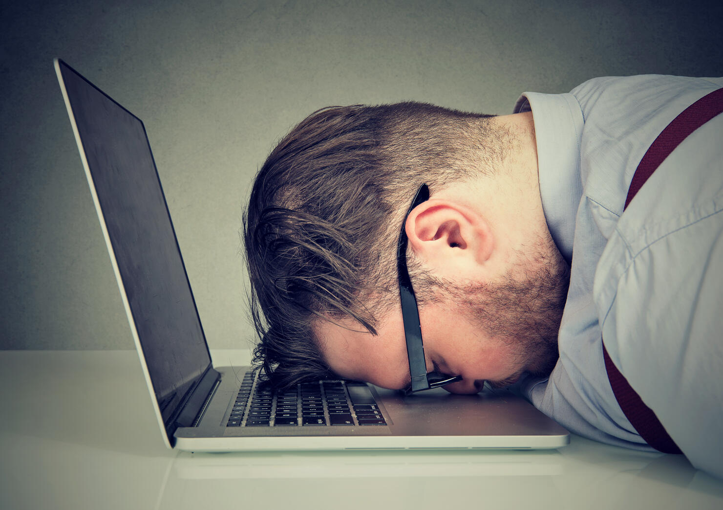 Overworked man lying on laptop