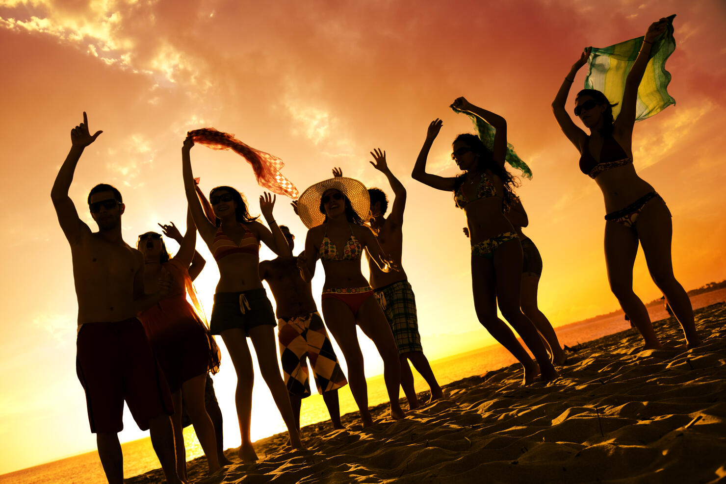 Spring break backlit group of young people dancing on beach