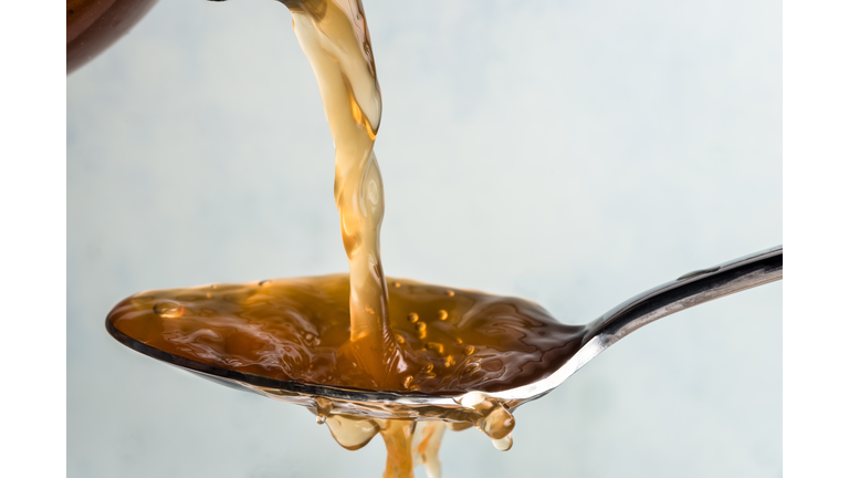 Close-Up Of Vinegar Pouring In Spoon Against White Background