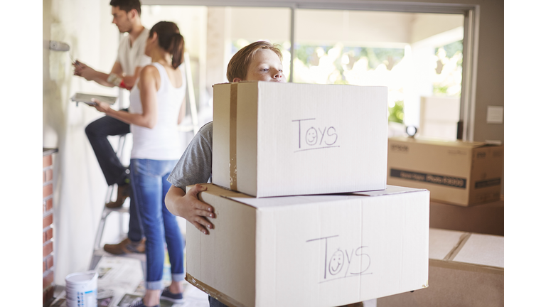 Family moving house, boy carrying boxes