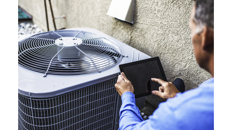 Maintenance engineer using digital tablet to inspect air conditioning unit