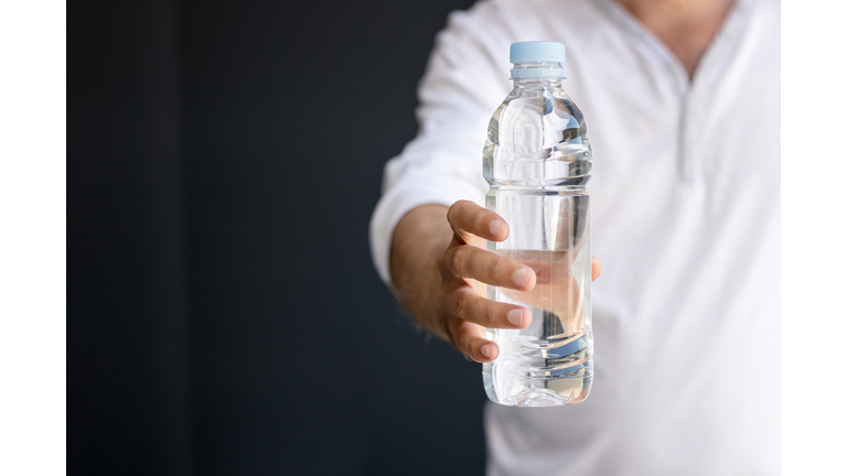 Midsection Of Man Holding Water Bottle Against Black Background