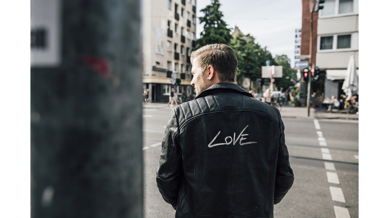 Back view of young man wearing black leather jacket with writing 'Love'